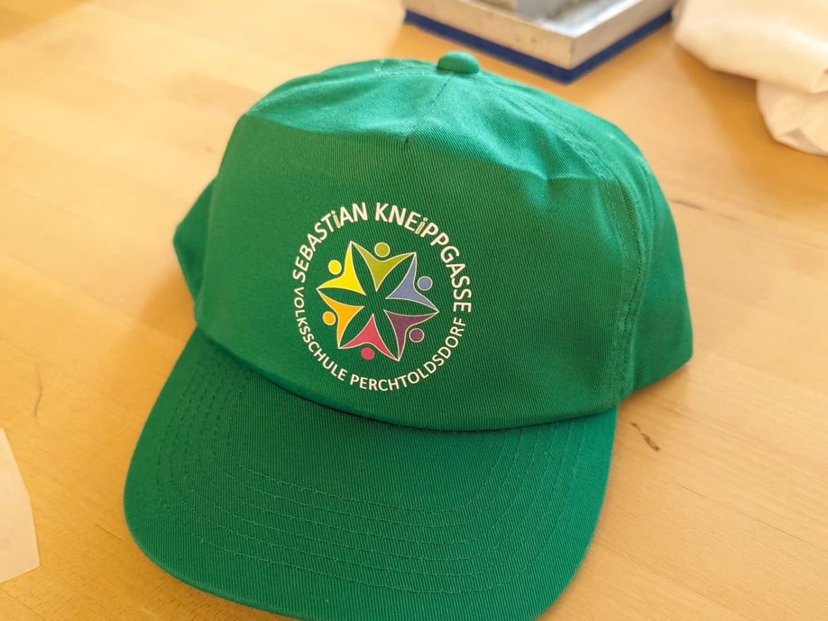 Grüne Schulcap mit bedrucktem Logo der Volksschule Perchtoldsdorf